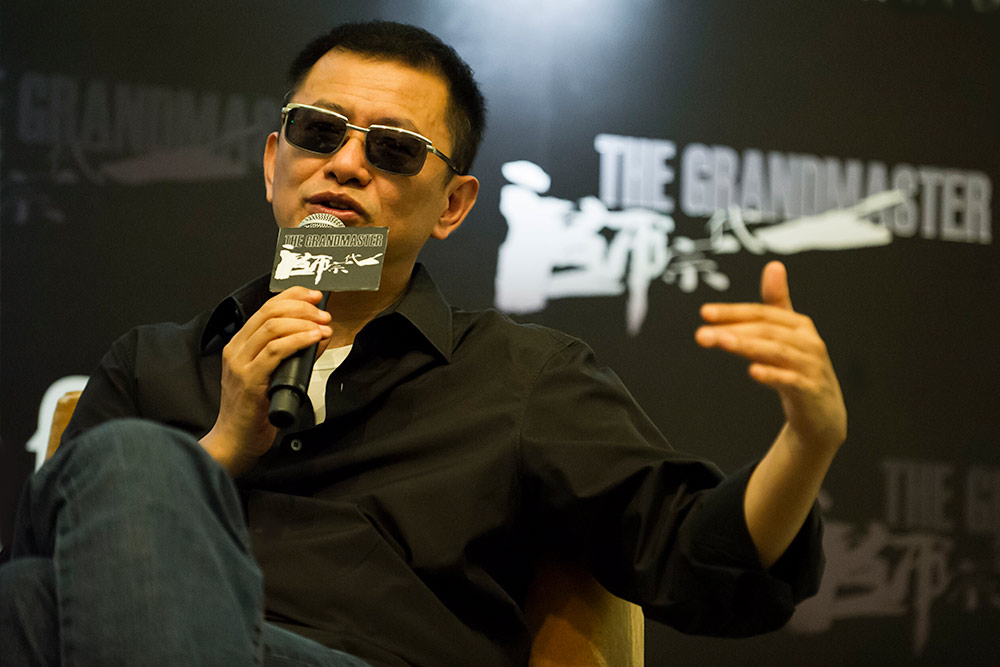 director Wang Kar-wai speaking into a microphone while seated