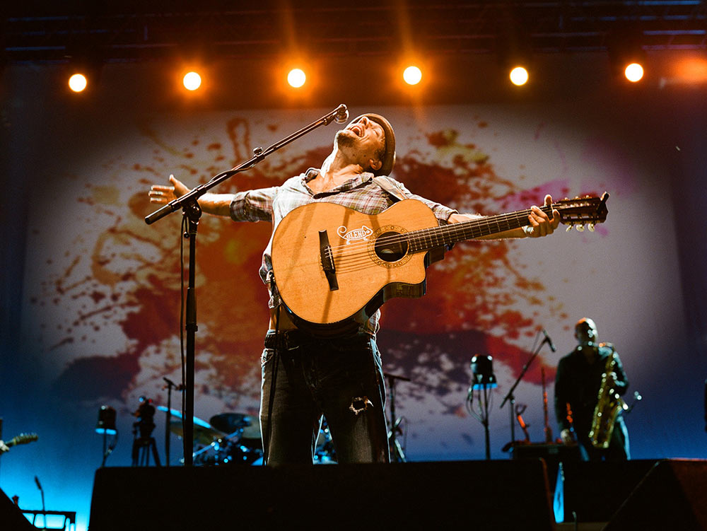 Jason Mraz singing with arms outstretched, head thrown back