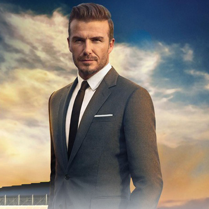 David Beckham in a suit standing in front of a luxury resort