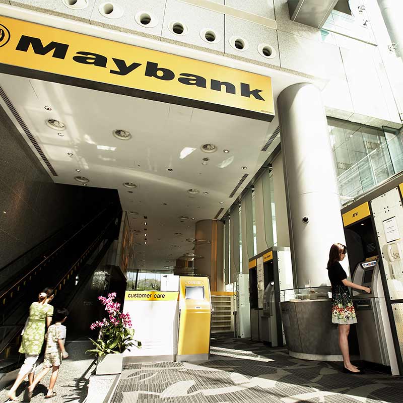 woman using ATM in Maybank's lobby in Singapore's financial district