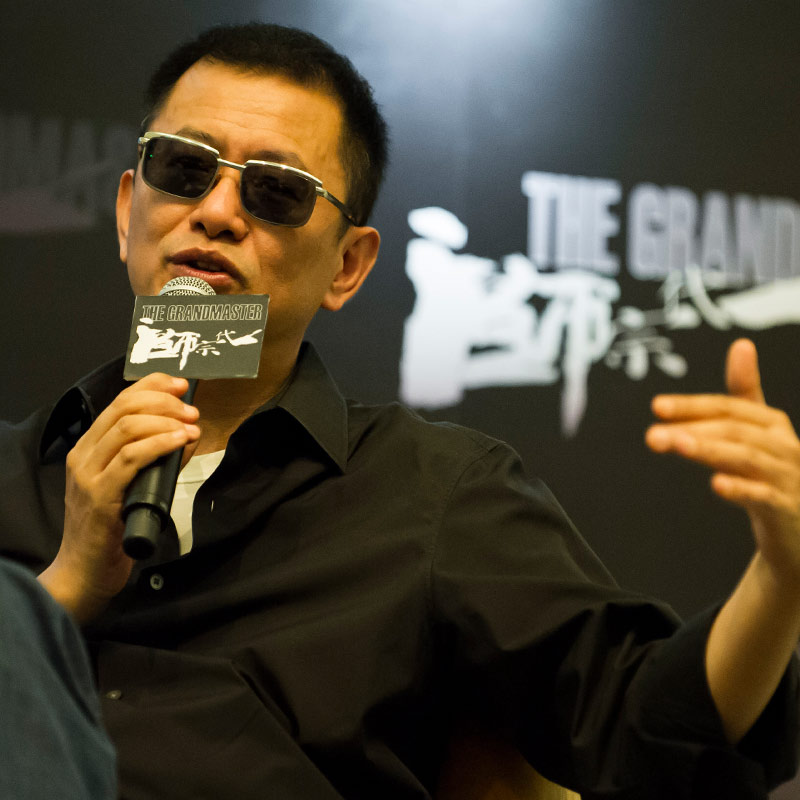 director Wang Kar-wai speaking into a microphone while seated